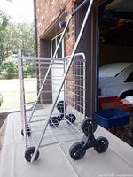 Side view of metal cart showing tri-wheel stair-climbing assembly and handle