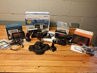 All four GPS units with boxes, mounts, cables and accessories displayed on tabletop