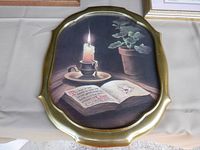 Gold oval framed still life print with lit candle and open prayer book