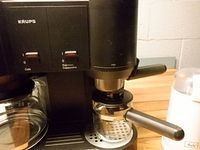 Front view of Krups machine with portafilter and carafe plus Melitta grinder