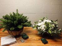 Both hanging baskets with artificial greenery/flowers and battery packs on table