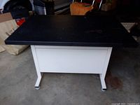 Front view of the metal table showing black top and white base