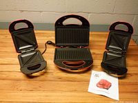 All three appliances open showing grill and sandwich plates on wooden surface