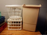 Trash can, laundry basket and white crate side by side