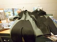 Both wetsuits laid out with stacks of magazines visible