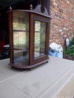 front oblique view showing glass door, curved sides, finials, overall style