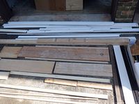 Assorted baseboard, chair rail, quarter round, 2x4 and misc wood laid on driveway