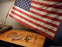 Flag on wood pole with wind spinners and chime on table