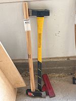 Two axes leaning against wall with wedges on floor