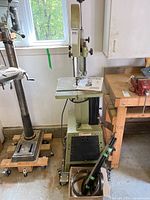 Front view of Craftex 14 in. band saw on mobile base with manual on table and accessory box in front
