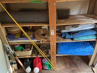 Shelving with tarps, soil, fencing rolls, coil, stakes, tools and fertilizer