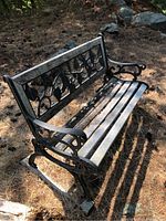 Full view of bench showing metal frame, decorative back, wood slat seat