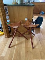 Both folding tripod stools standing side by side