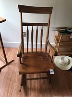 Front view of wooden rocking chair showing spindle back, arms, seat and rockers