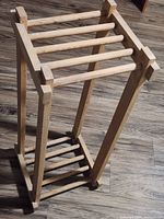 Angled view of full pine plant stand showing top and lower slatted shelves