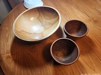 Large bowl and two smaller bowls on wooden surface