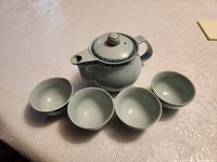 Teapot with lid and four cups displayed