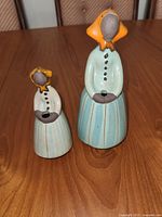 Front view of both glazed ceramic faceless women figurines