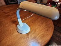 Full view of OttLite table lamp on table, showing base, flexible neck, and shade