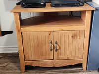 Front view of Sauder corner cabinet with devices on top