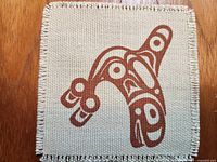 Close-up of single coaster showing brown motif and fringed edge