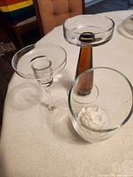 Three candle holders: clear stemmed dish, amber-stemmed holder, cylindrical votive