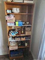 Front view of tall oak veneer bookcase filled with assorted items