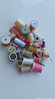 Pile of assorted coloured thread spools, bobbins and chalk