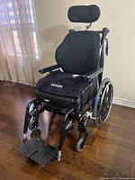 Front-left view of wheelchair showing frame, cushion, wheels and footrests