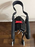 Front view of NeXus rollator showing seat, handles, red strap, four wheels