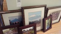 Group of five framed artworks leaning against wall