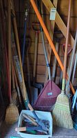 Group of long-handle tools: brooms, rake, shovels, hoe