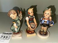 Front view of the three Hummel figurines together showing size and details