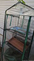 Front view of greenhouse showing cover, frame, shelves, tray and potting mix bag
