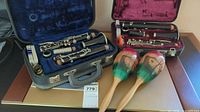 Two open clarinet cases showing instruments and pair of maracas