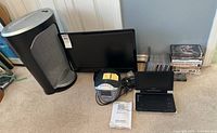 Lot overview showing shredder, HDTV, CD clock radio, portable DVD player, CDs and VHS tapes
