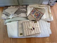 Group view of assorted table linens: damask tablecloth, lace-trim napkins, embroidered runner, quilted placemats, white quilted cover