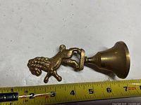Front view of brass bell showing lion handle and measurement indicating roughly 5 in. length