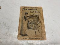 Front cover of first cookbook with woman at stove