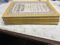 Stack of four National Geographic magazines showing spines with dates and volume numbers