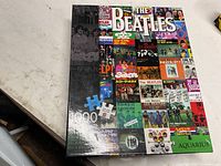 Box front showing The Beatles collage 1000-piece puzzle by Aquarius