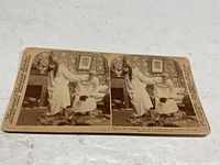 Front of sepia stereograph card showing bedroom scene with two women and dog