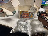 Overall view of aluminum Garfield mold halves with torn box in background
