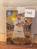 Front view of 2024 Bowman Chrome Gladiators of the Diamond Samuel Basallo gold parallel card showing serial number 11/50 in plastic sleeve