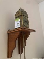 Lantern clock on oak wall bracket, front view