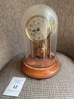 Front view of clock under glass dome on wood base