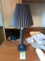 Full view of lamp with shade, cord, surrounding context