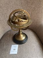 Front view of brass and wood armillary sphere on chair