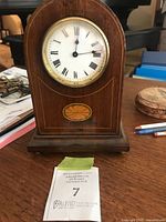 Front view of dome-topped mahogany mantel clock showing dial and inlay