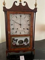 Front view showing full clock, dial, eglomise panel, finials